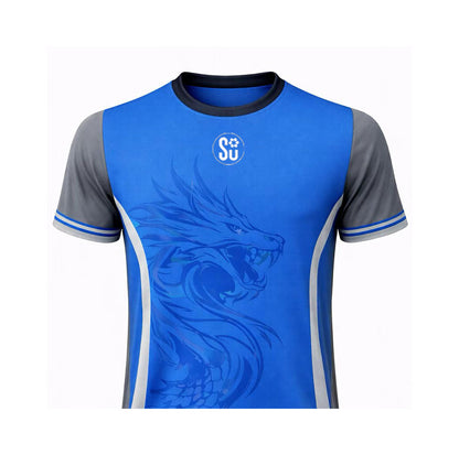 The UMPIRES Elite Uniform by Southern Apparel is a breathable, lightweight blue sports jersey with gray short sleeves, showcasing a large stylized dragon graphic on the front and a small white circular SU logo near the collar.
